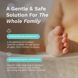 A promotional graphic for a gentle baby cleanser, featuring a close-up of a baby's foot resting in a bathtub. The image includes text overlays highlighting 'A Gentle & Safe Solution For The Whole Family' along with 'PEDIATRICIAN APPROVED' and 'DERMATOLOGIST APPROVED' badges.