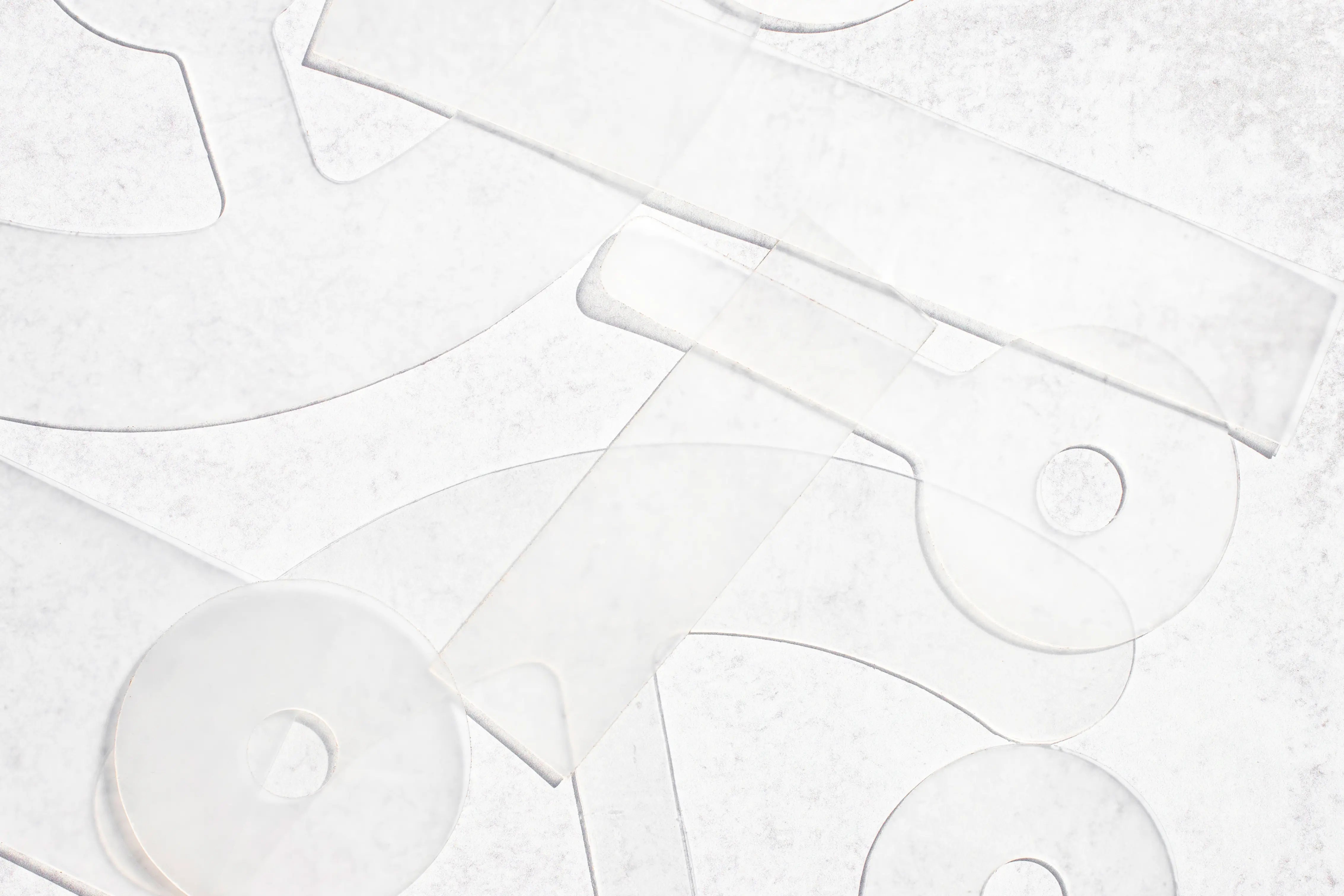 Clear acrylic craft templates with geometric shapes and circular pieces scattered on a textured white background.