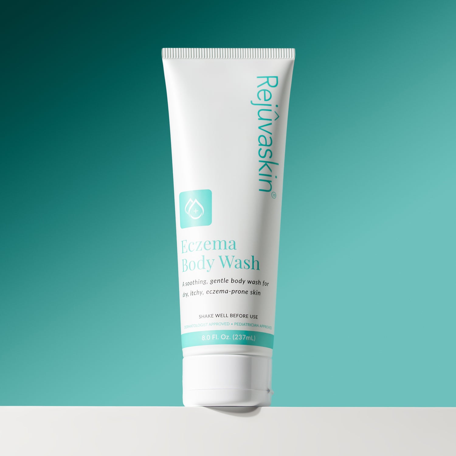 A white squeeze tube of Rejuvaskin Eczema Body Wash with teal text and icon, standing upright on a white surface against a teal gradient background.